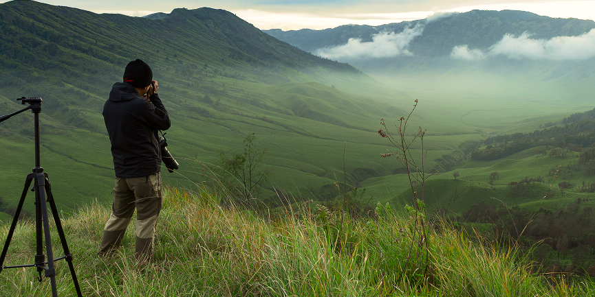 Fotograf in beeindruckender Landschaft nimmt Naturfotos mit professioneller Kamera auf – Inspiration für Landschaftsfotografie.